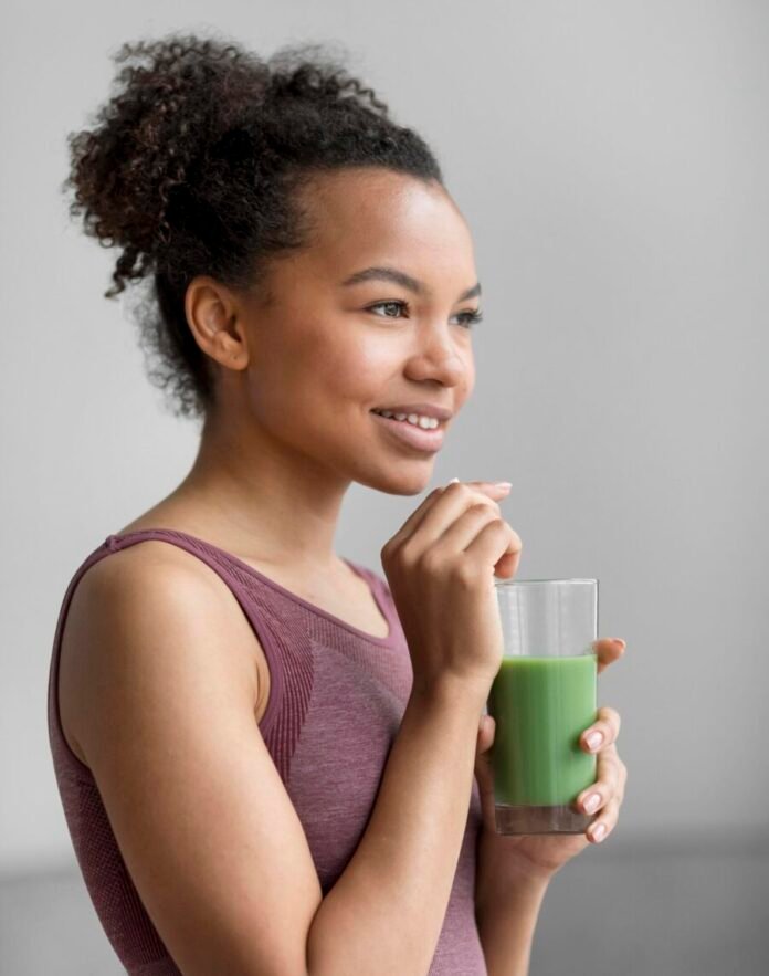uma jovem morena, tomando um suco detox.
