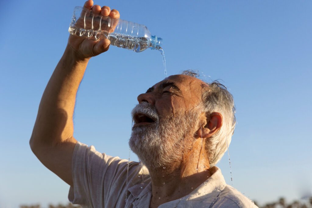 idoso se refrescando jogando agua na cabeça.