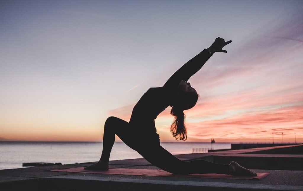 silhueta de uma jovem praticando yoga ao entardecer.