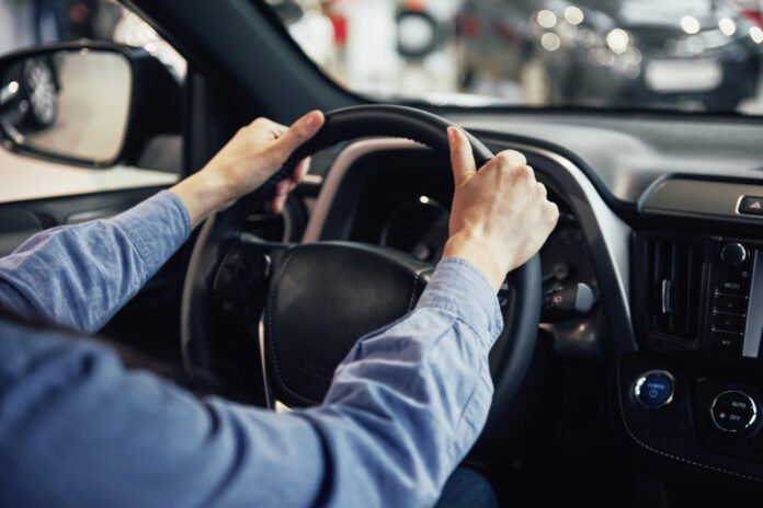 imagem do tronco de uma pessoa dirigindo um carro