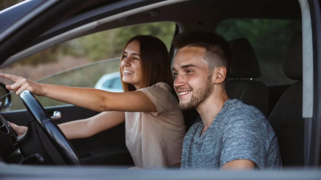 casal jovem com a mulher dirigindo o carro.