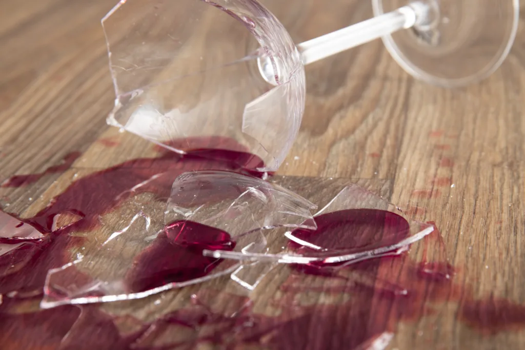 taca de vinho quebrada com ovinho tinto derramapo sobre a mesa.