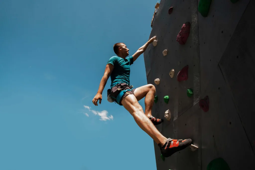 um jovem fazendo escalada indoor. 