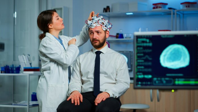 cientista realizando pesquisas em um paciente através de eletrodos na cabeça.