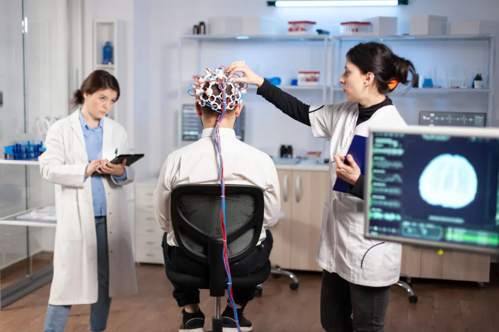 médicos realizando testes cerebrais usando um capacete com eletrodos.