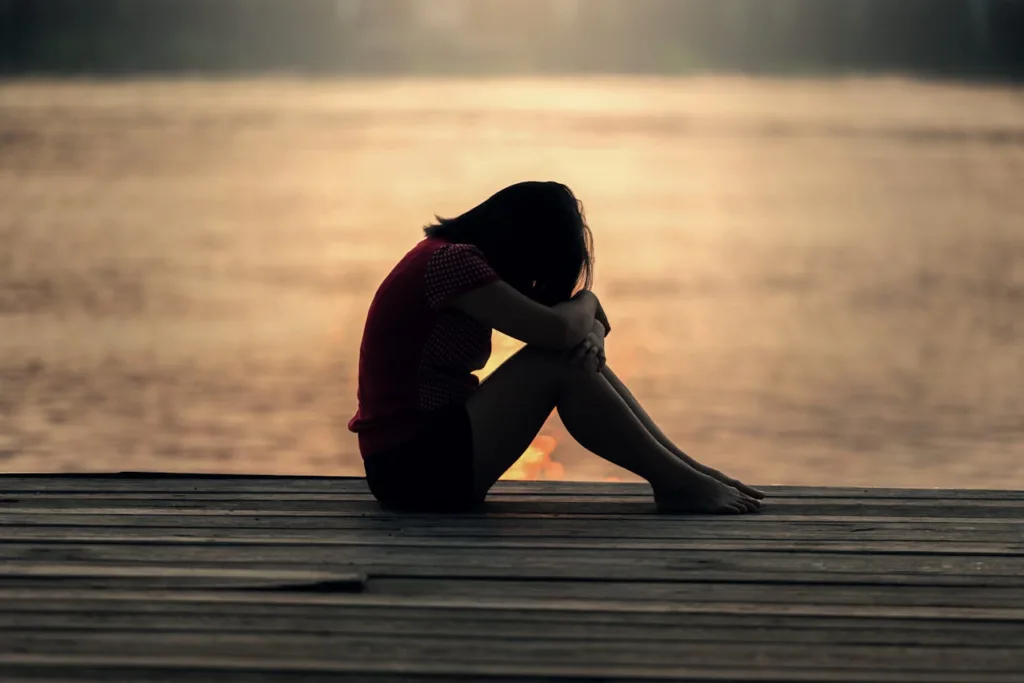mulher em situação de depressão ao ar livre ao por do sul.