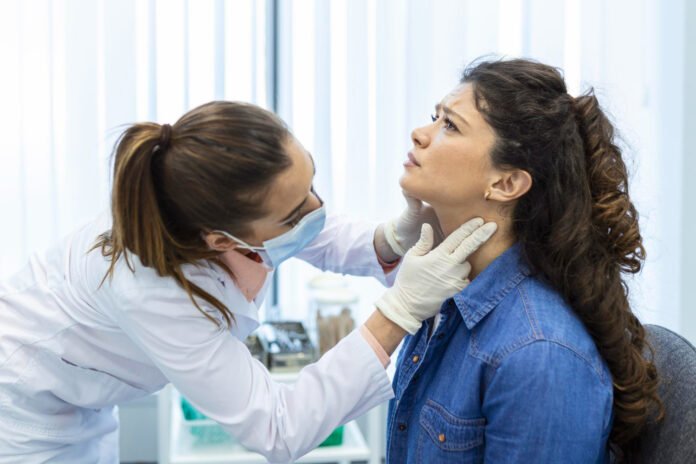 medica examinando a tireoide de uma paciente.