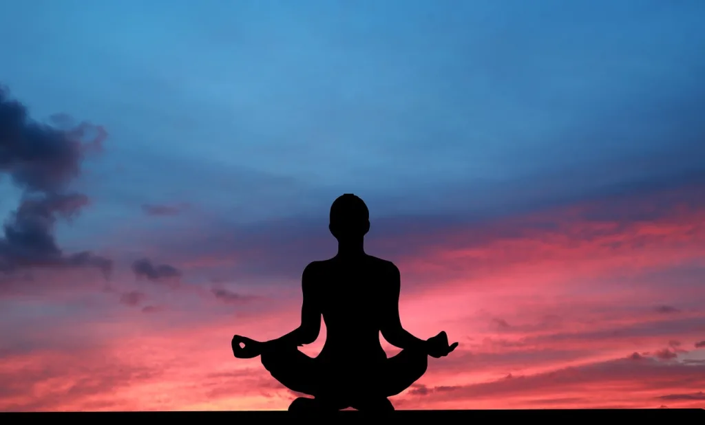 silhueta de uma mulher em posição de yoga num fundo colorido.